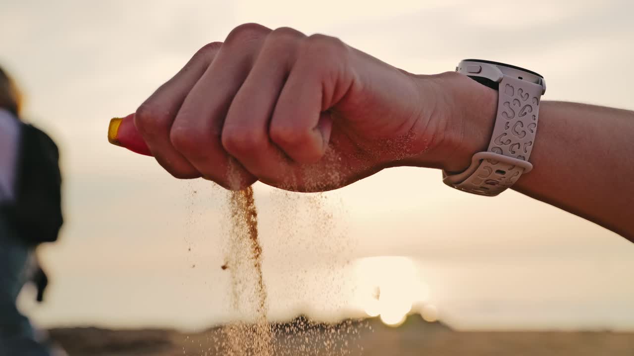 Sand Falling Through Woman's Fingers at Sunset