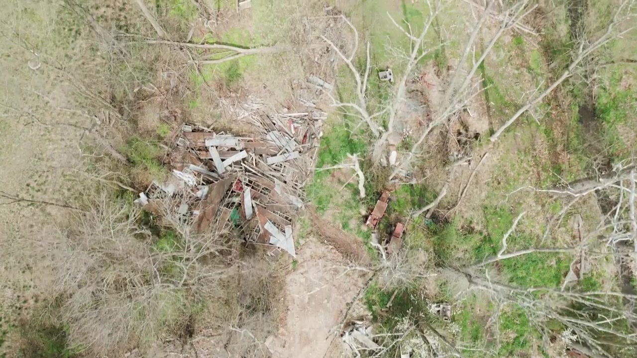 moving aerial shot over a forest full of junked cars and scrap metal