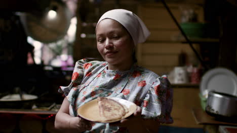 woman showing tortilla in a plate