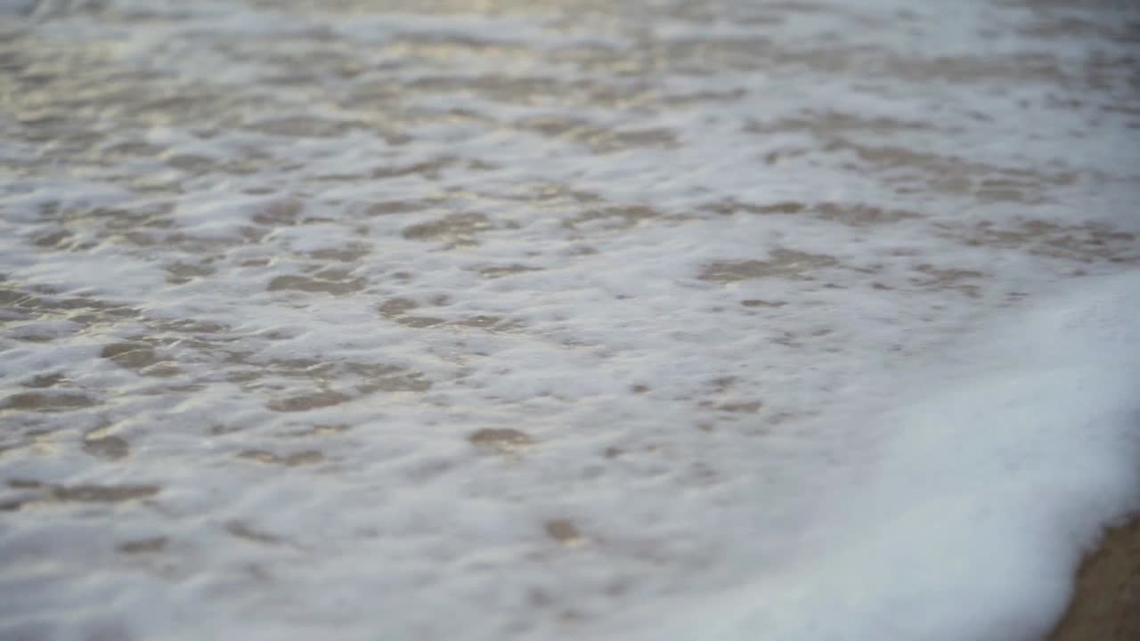 Waves washing sandy beach in slow motion
