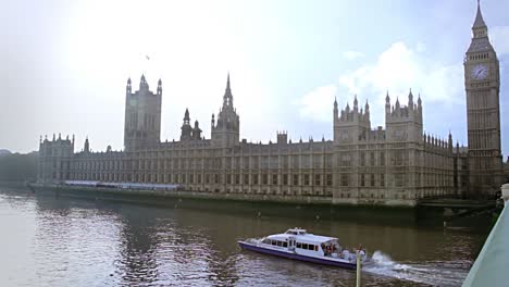 casas del parlamento con un largo barco turístico que atraviesa el río támesis en un día muy soleado en londres, inglaterra