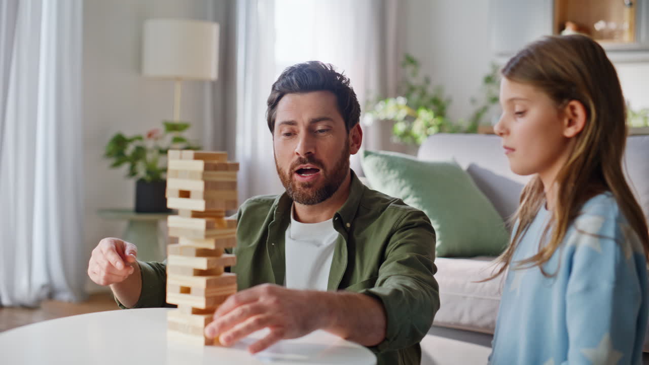 Primo piano di padre e figlia che giocano a jenga in soggiorno. Uomo sorridente che costruisce una torre