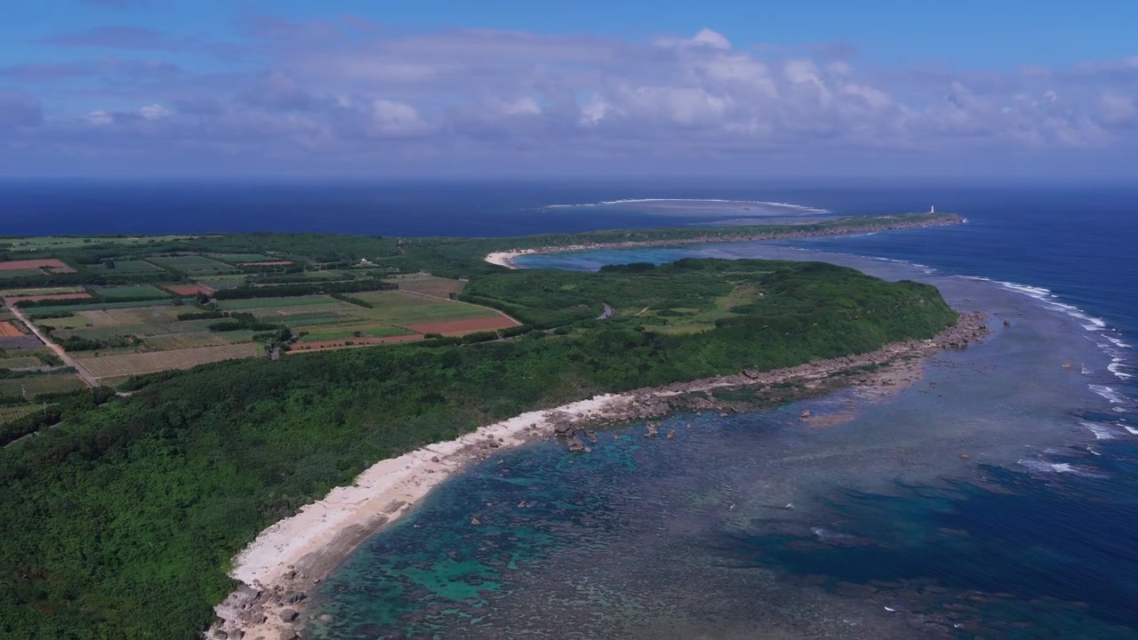 Riprese aeree orizzontali con carrello all'indietro sopra la spiaggia di Boraga, la costa frastagliata e il faro di Hennasaki, Miyakojima, Okinawa, Giappone.