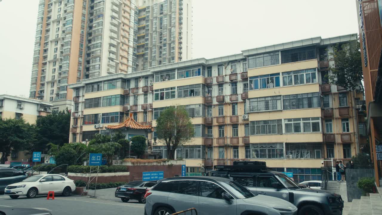 Antigo Edifício Residencial em Shenzhen com Grades de Segurança ao Lado de Arranha-céu Moderno e Estacionamento (1)