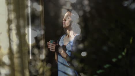 animation of white spots of light over biracial woman drinking tea