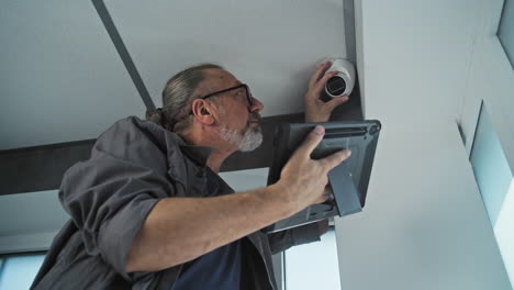 man installing or adjusting a security camera with a tablet