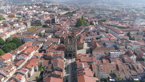 Gente-Fuera-Del-Antiguo-Edificio-De-La-Catedral-De-Braga-Rodeada-Por-Las-Casas-Con-Techo-De-Tejas-Rojas-En-La-Ciudad-De-Braga,-Portugal