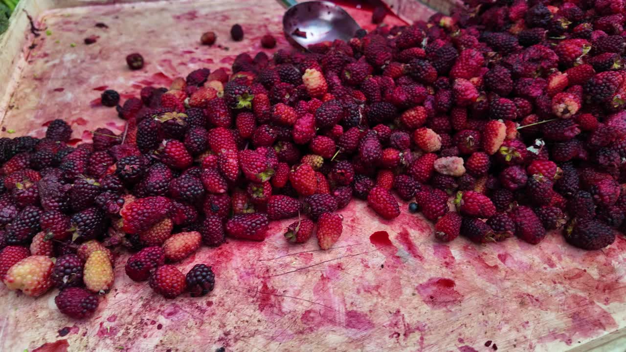 Seasonal fruit. Large pile of fresh ripe blackberries and strawberries, with a scoop at street market stall.