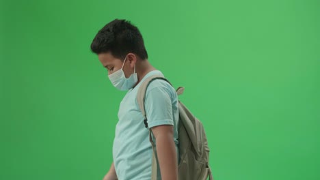 vista lateral de un estudiante asiático caminando a la escuela en pantalla verde tecla de croma