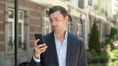 portrait man using smartphone outdoor. businessman typing on phone at street