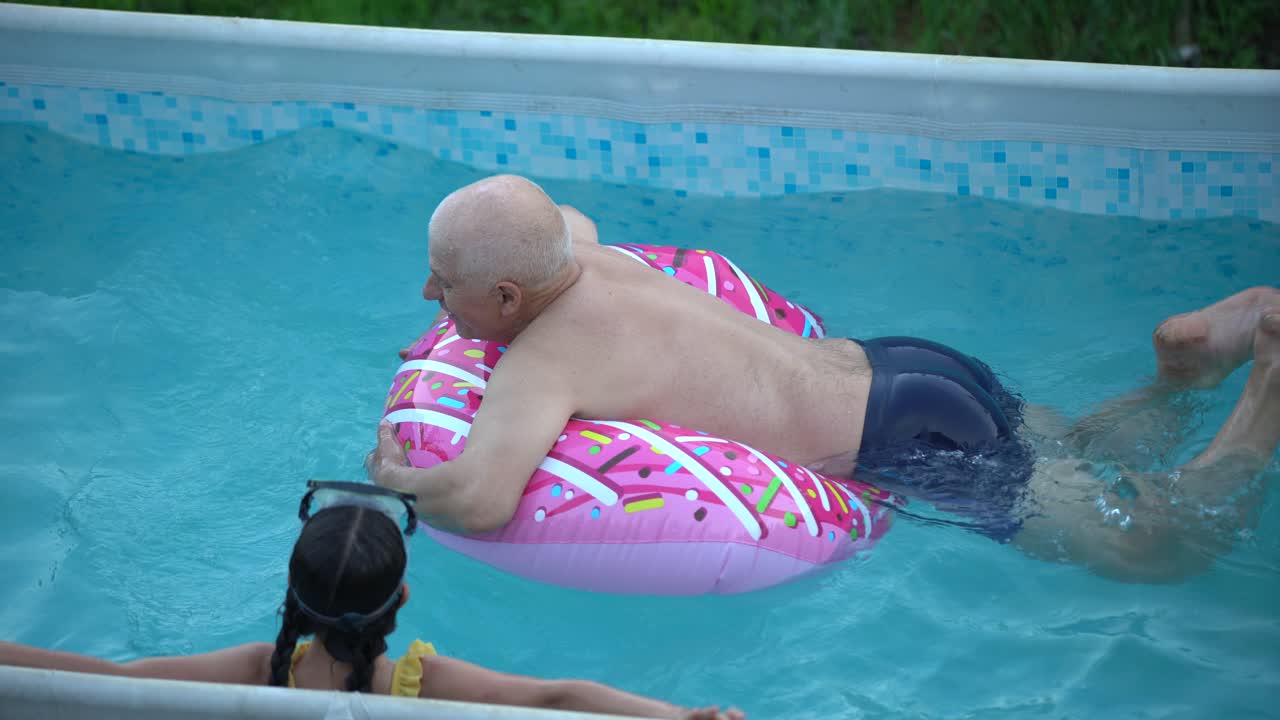 abuelo y nieta nadando en la piscina