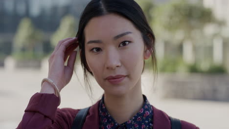 portrait successful young asian woman student running hand through hair smiling enjoying comfortable urban lifestyle in city beautiful independent female sunny outdoors slow motion