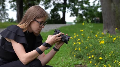 Perfil-De-Una-Joven-Fotógrafa-Con-Cámara-Tomando-Fotos-De-Flores-En-El-Parque-A-Cámara-Lenta-De-Fotograma-Completo