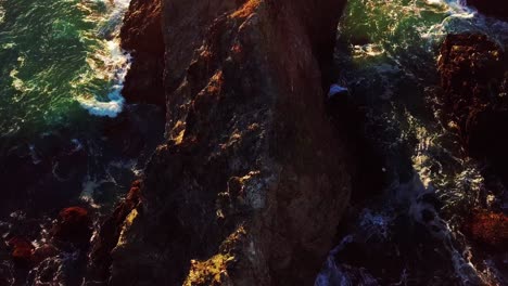 Last-sun-of-day-lights-green-ocean-waves-crashing-into-rocky-cliffs-in-Big-Sur-California