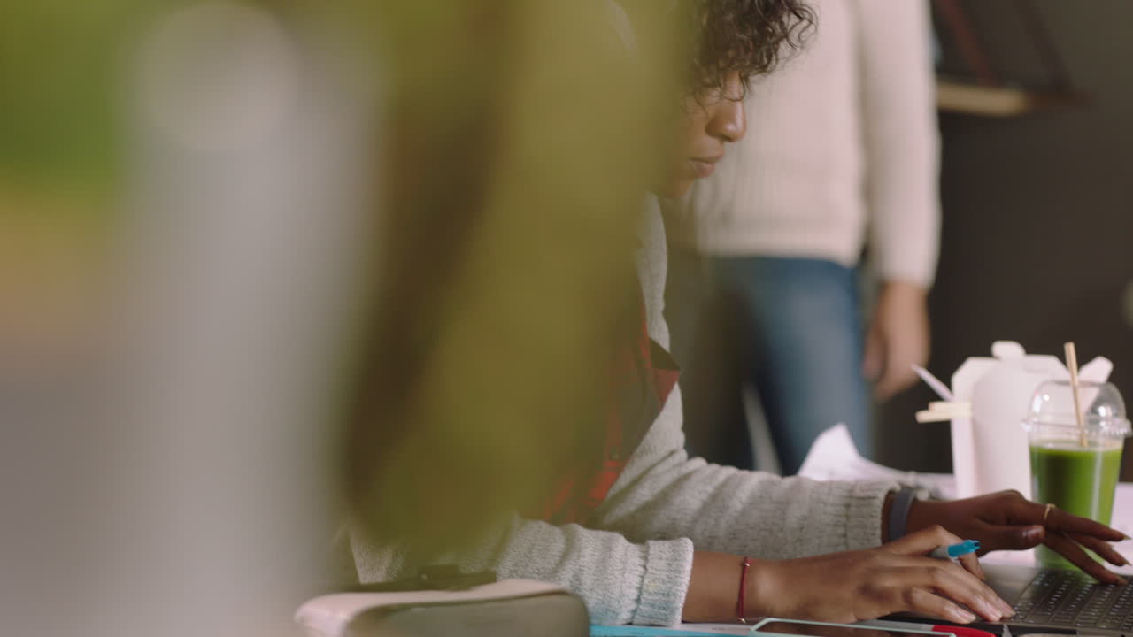 joven mujer afroamericana estudiante usando computadora portátil digital escribiendo notas haciendo lluvia de ideas de negocios navegando en línea estudiando escuchando música usando auriculares en la oficina