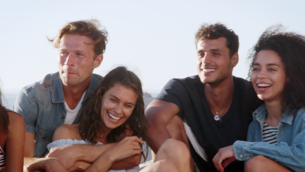 Gruppo di amici seduti in spiaggia e che chiacchierano in vacanza estiva