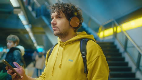 man in headphones using phone and vibing in subway