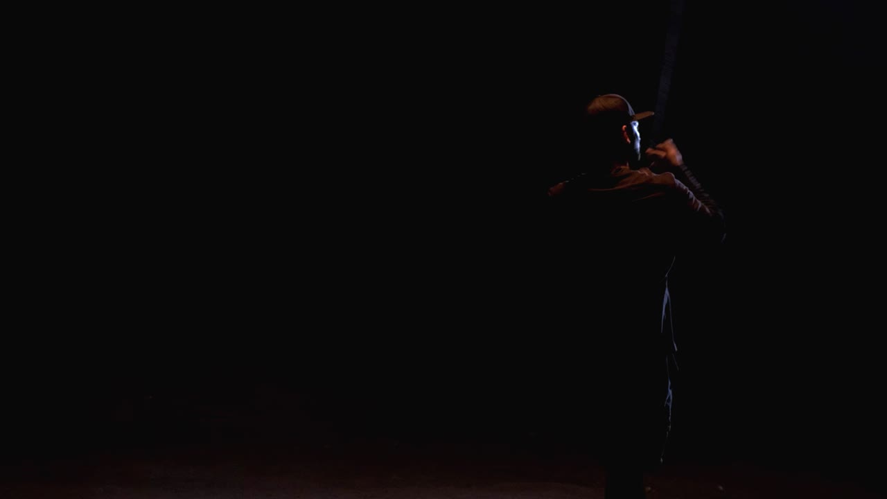 A man twists and throws a fire rope in an abandoned place. Night performance. Fire show. Slow motion
