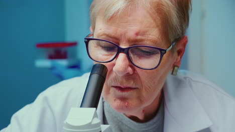 primer plano de un científico sénior haciendo una investigación usando un microscopio