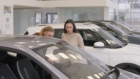 una hermosa pareja de jóvenes en la sala de exposición de automóviles eligiendo un coche nuevo para comprar.