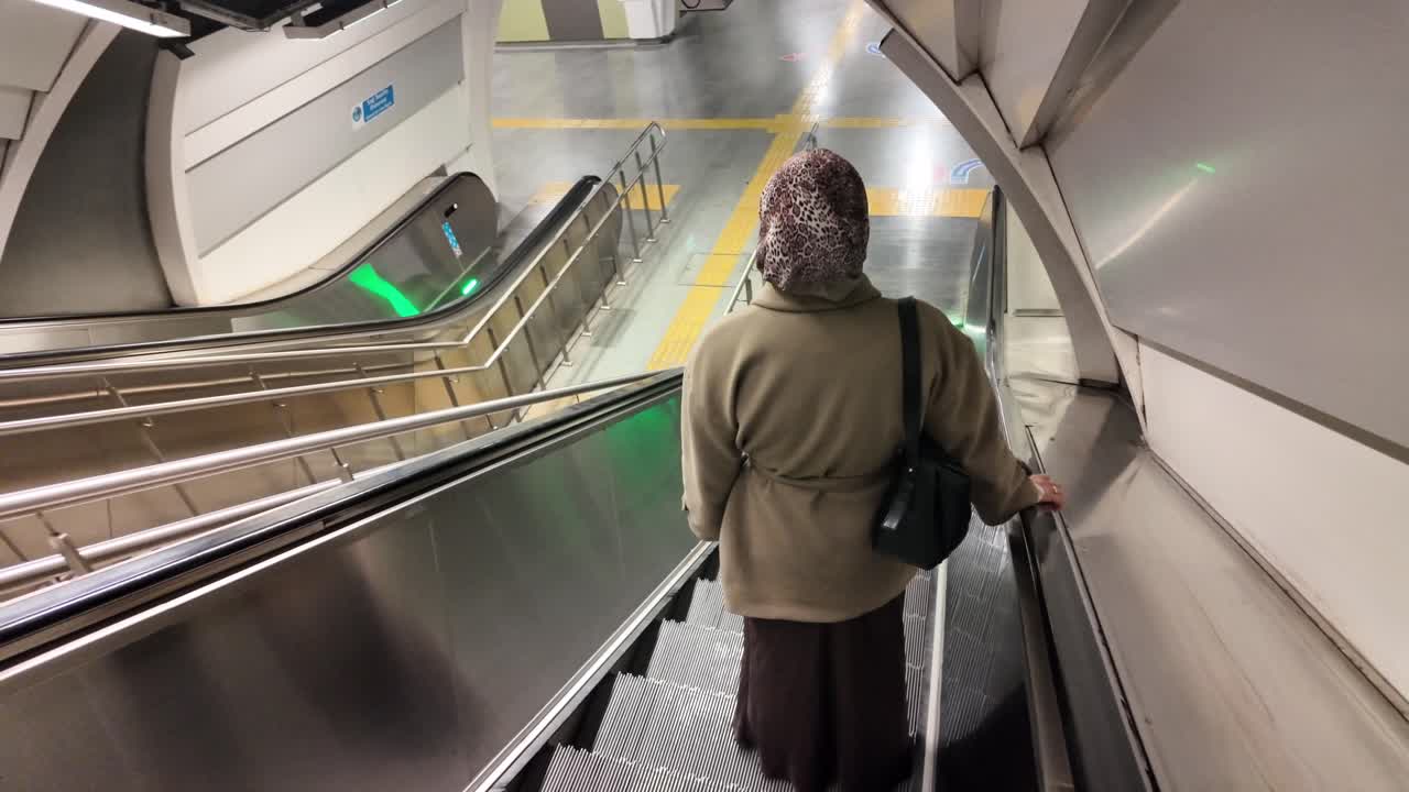 Frau fährt Rolltreppe in moderner U-Bahn-Station hinunter