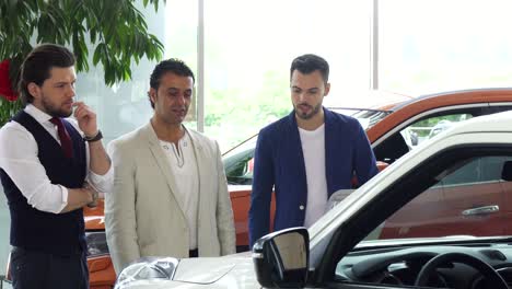 three male friends examining car for sale at the dealership