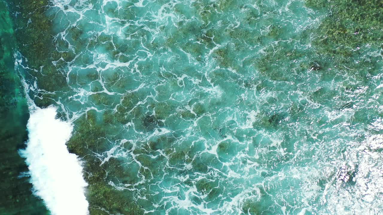 White wave splashing over rocky seabed making foam over calm lagoon with clear seawater, creating beautiful texture, copy space