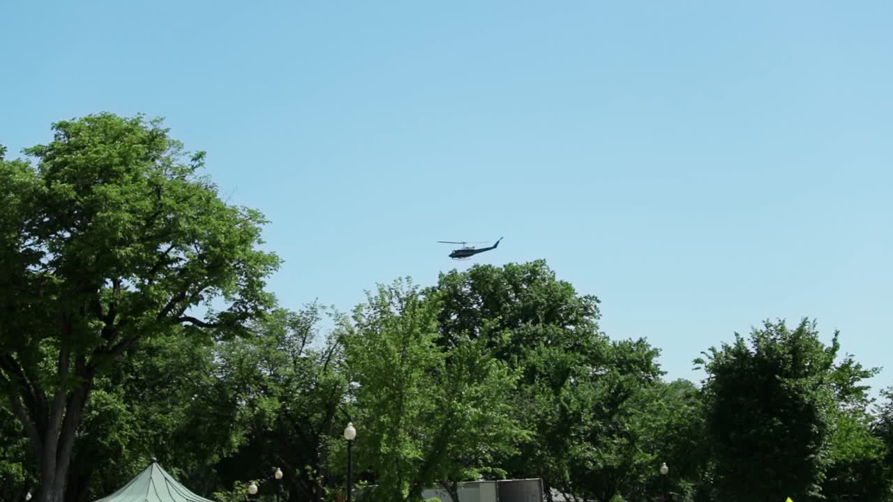 Low altitude flying helicopter in the distance over trees near the Lincoln Memorial site in Washington, DC, USA.