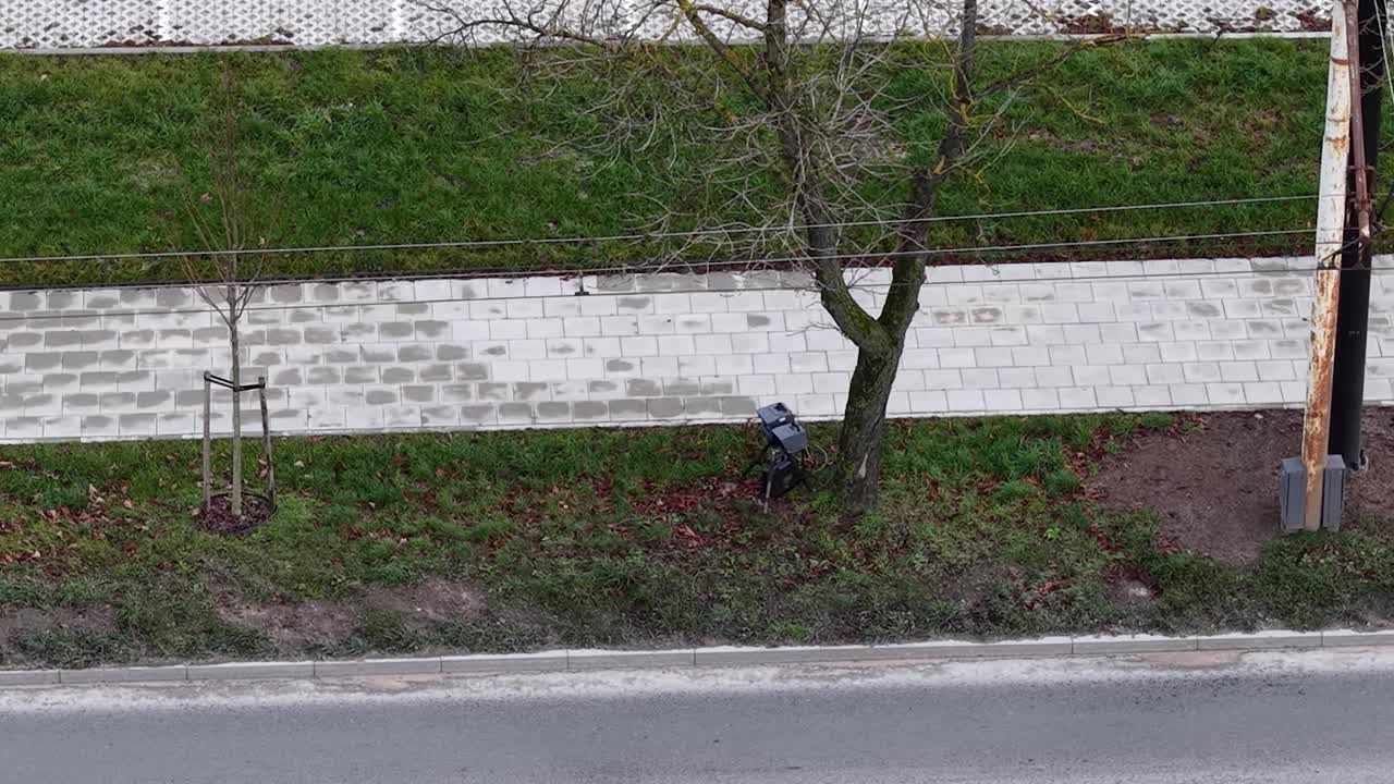 Mobile speed camera hidden behind tree near street, aerial orbit view