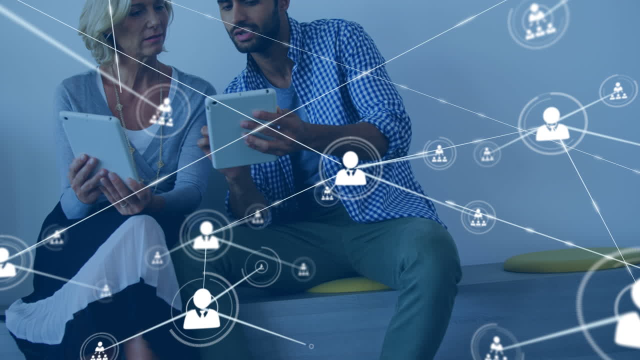 Animation of network of connections with icons over caucasian man and woman using tablets