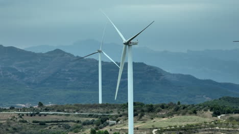 Vista-Panorámica-De-Paralaje-Aéreo-De-Aerogeneradores-Eólicos-En-El-Paisaje-Montañoso-Rural-En-Un-Día-Nublado-En-Coll-De-Moro-En-Cataluña,-España