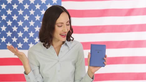 joyful woman celebrating immigration with passport in front of american flag