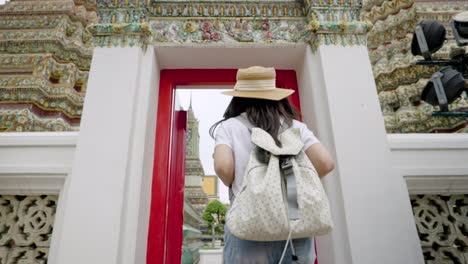 cheerful young asian woman traveling at wat pho temple in bangkok, thailand.