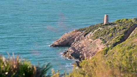 relaxing footage of a standalone defensive medieval tower by the mediterranean turquoise water in oropesa del mar, spain