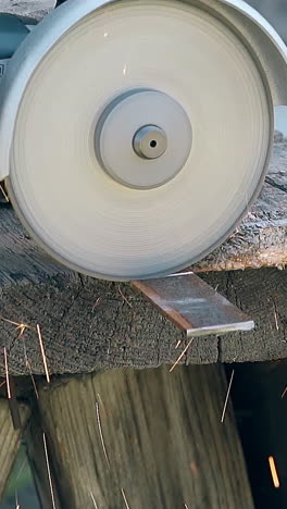 slow motion closeup powerful circular saw cuts part of metal plank under sparks shower on wooden table