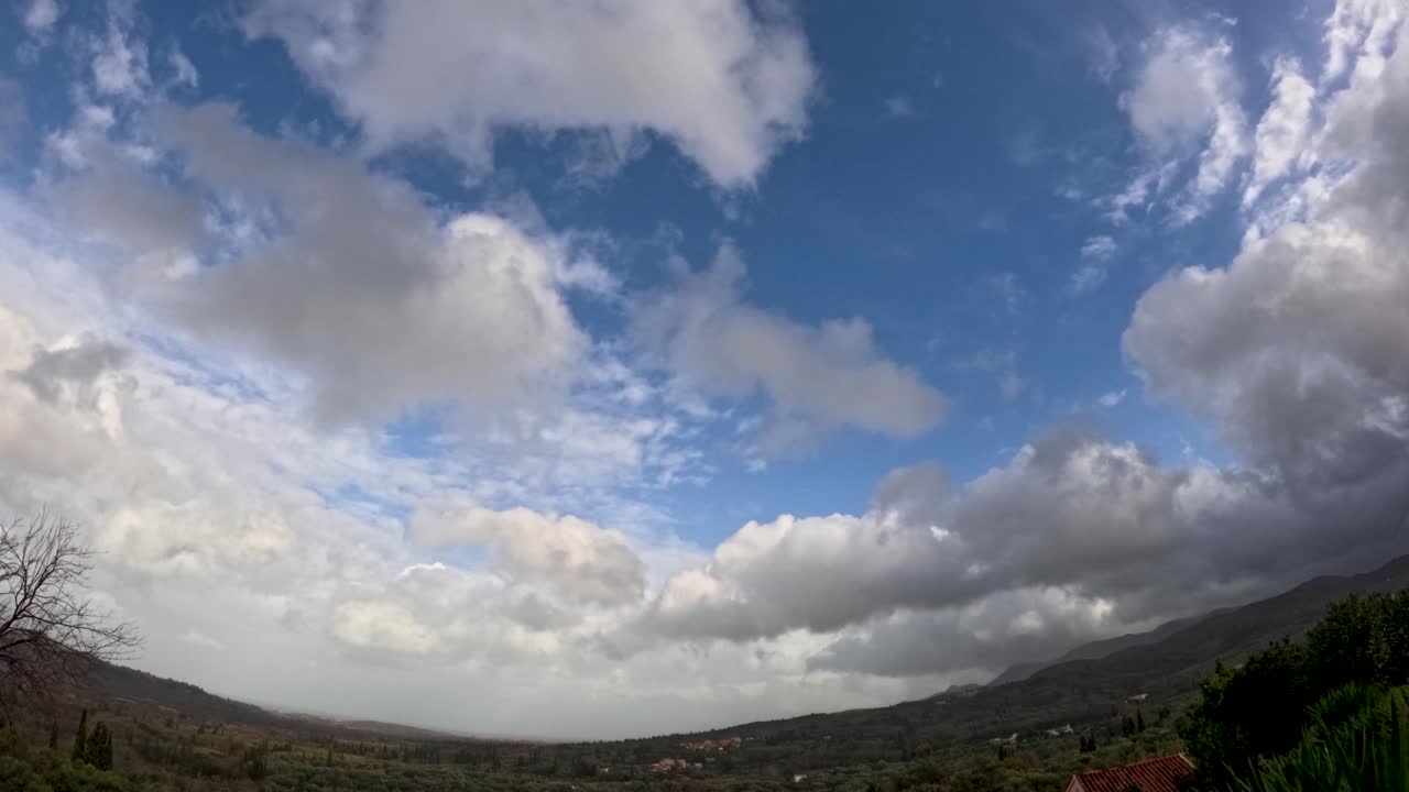 Time lapse panoramico di soffici nuvole cumuliformi bianche che si spostano su una valle verde e sulle colline di Corfù, in Grecia, in una giornata di sole con cielo azzurro