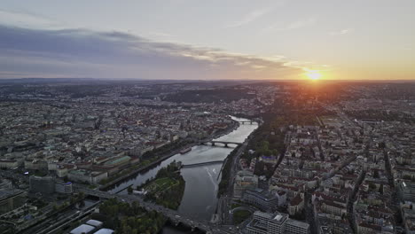 Prague-Czechia-Aerial-v65-reverse-flyover-Holesovice-capturing-Vltava-river,-Stvanice-island,-riverside-cityscape-with-beautiful-golden-sunset-on-the-horizon---Shot-with-Mavic-3-Cine---November-2022