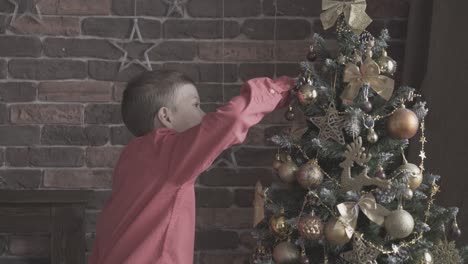 boy touches with admiration golden toys on christmas tree