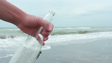 young man closing message in a bottle on sand beach