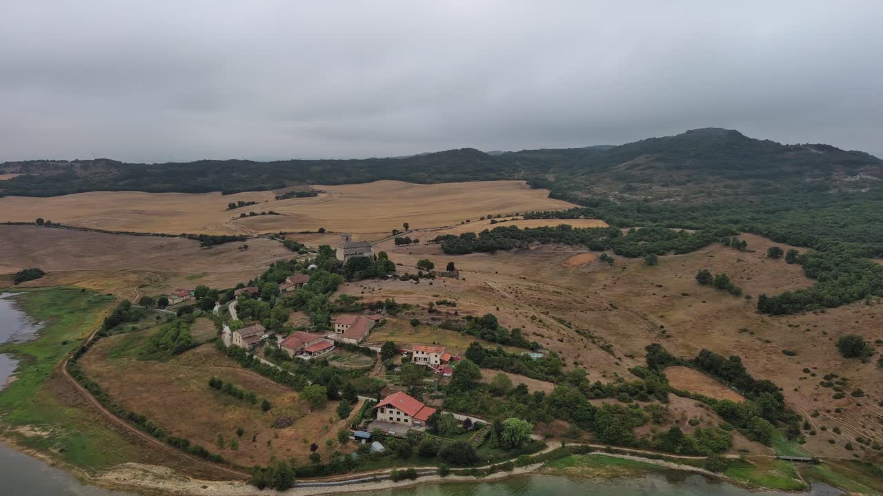 aldea de nanclares de gamboa en el país vasco, españa, con cielos nublados y alrededores exuberantes, vista aérea