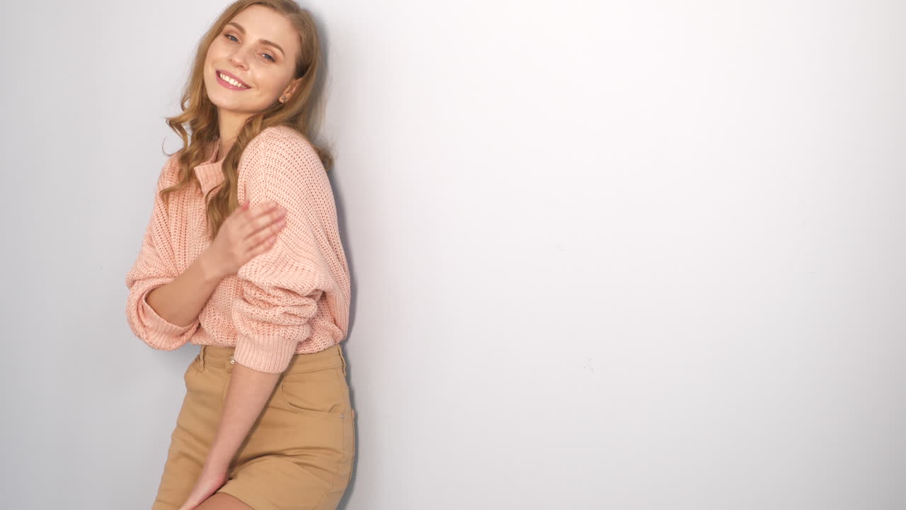 mujer con un suéter rosa y pantalones cortos caqui