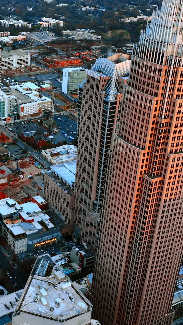 Panoramic view on the diverse architecture in the downtown of Charlotte, North Carolina, USA. Cityscape in the rays of setting sun from top. Vertical video