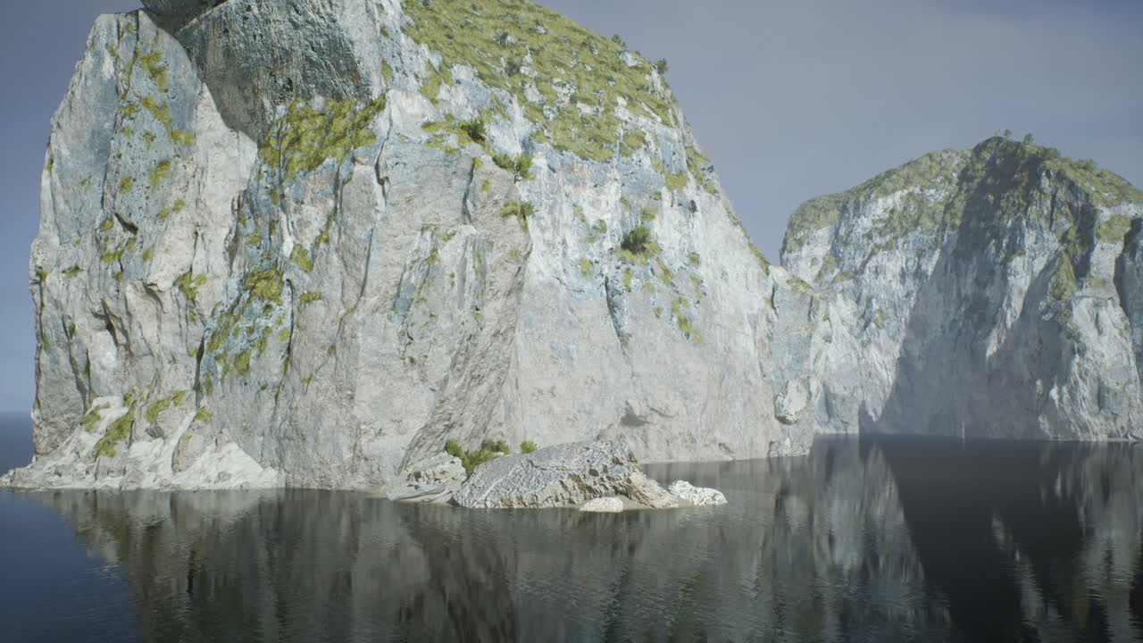 Tranquil misty cliffs beside shadowed waters and hazy distant horizon