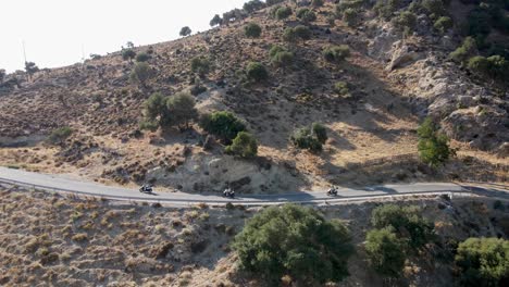 Parallel-drone-shot-of-three-scooters-driving-on-a-mountain-road-on-the-island-of-Kos