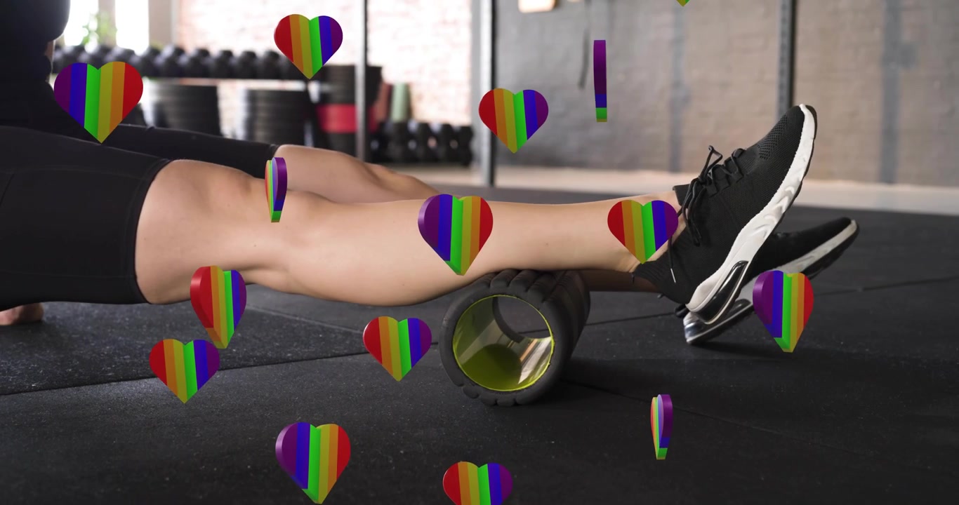 Woman placing foam roller beneath calf and rolling leg on rubber gym floor for fitness recovery