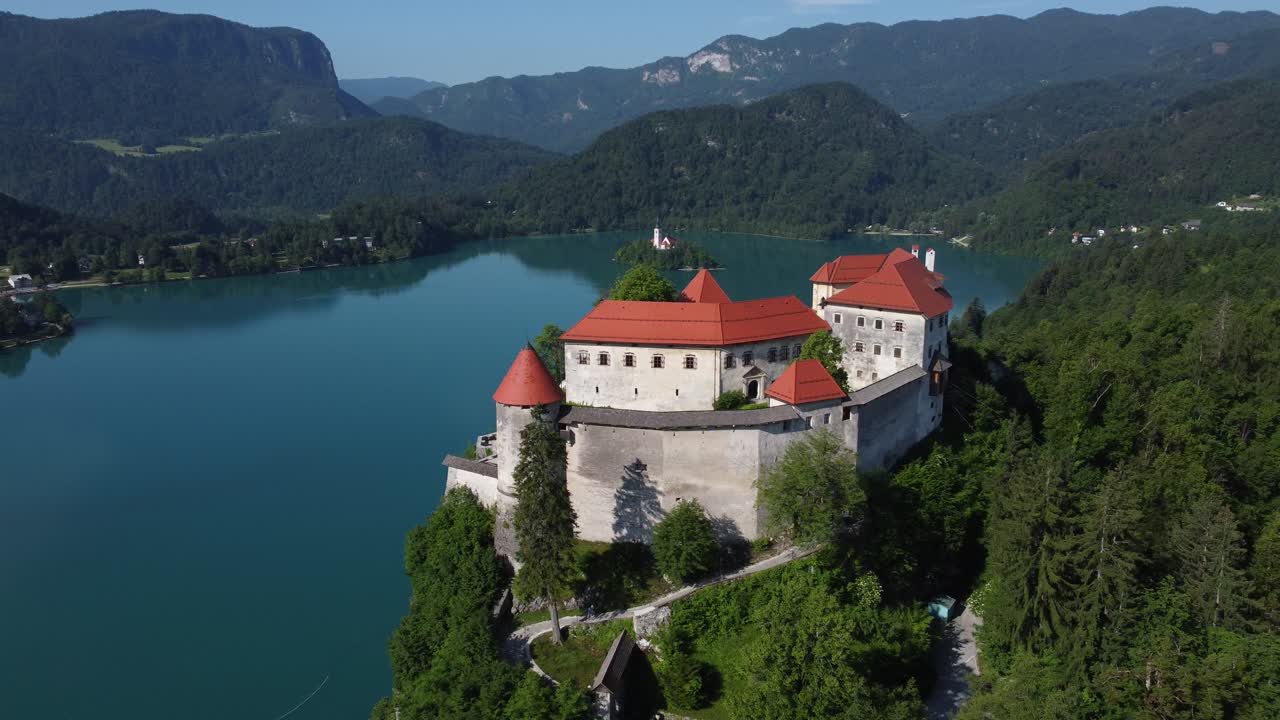 Panorama di lago glaciale alpino e castello con piccola isola. Filmato video stock di alta qualità 4K ripreso con drone.