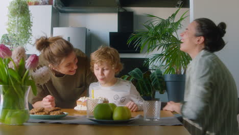 happy boy celebrating birthday with lesbian parents at home