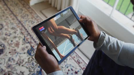 compuesto de un hombre sentado en casa viendo un evento de atletismo en una tableta