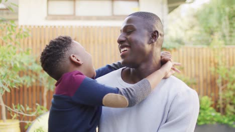 video de un feliz padre y hijo afroamericanos abrazándose en el jardín