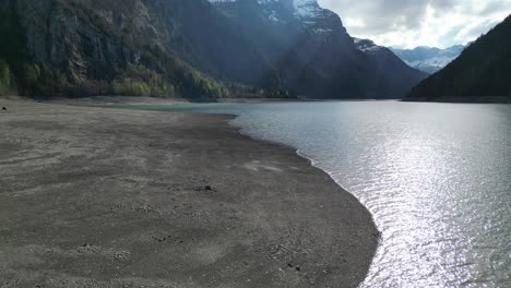 aerial forward view of shoreline of an alpine lake in a fantastic mountain landscape